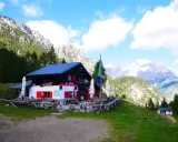 Rifugio Antelao, con le sue persiane rosse, accoglie i visitatori anche in ottobre, immerso in un paesaggio alpino mozzafiato.