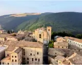 Borgo con torre dell'orologio, immerso nel verde delle colline. Chissà se è questo il borgo dei borghi vincitore.