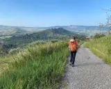 Escursionista con zaino arancione su sentiero panoramico, immersa nella natura della **Calabria coast to coast**.