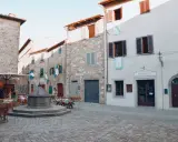 Piazza di San Donato in Poggio con pozzo antico, tavoli all'aperto e l'insegna "Osteria Numero Uno".
