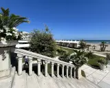 Scalinata in pietra con vasi fioriti, vista su una spiaggia ordinata con cabine bianche, tipica di una città di mare veneto.