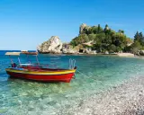 Barca rossa e gialla in acque cristalline, con isolotto verdeggiante sullo sfondo. Un angolo di paradiso che ricorda la bellezza di Sicilia e Sardegna.