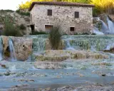 Cascate termali naturali con un antico mulino in pietra, un'oasi di benessere nel cuore delle terme centro Italia.