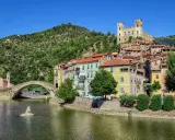 Borghi entroterra ligure levante: un ponte antico attraversa un fiume, case colorate si affacciano sull'acqua, un castello domina la collina verde.