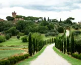Un suggestivo itinerario Val d'Orcia 2 giorni: strada bianca tra cipressi e colline verdi, con un borgo in lontananza.