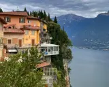 Case colorate aggrappate alla roccia a Tremosine sul Garda, con il lago e le montagne sullo sfondo.