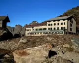 Rifugio alpino con piccola cappella, un esempio di cosa vedere in Lombardia, immerso in un paesaggio roccioso sotto un cielo stellato.