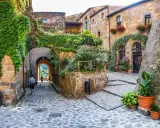 Un vicolo acciottolato tra antichi borghi da visitare nelle Marche, con case in pietra ricoperte di edera e fiori colorati.