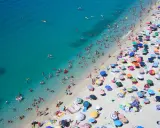 Spiaggia affollata con ombrelloni colorati e bagnanti nell'acqua cristallina, un'immagine perfetta per scoprire le località di mare più economiche in Italia.