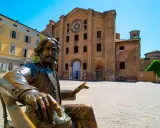 Statua di bronzo in piazza, con edifici storici sullo sfondo. Un assaggio delle città più belle Emilia Romagna.