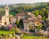 Borgo pittoresco con chiesa e campanile, colline verdi e fiori in primavera. Un luogo incantevole per scoprire cosa vedere a Golferenzo.