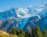 Ghiacciaio imponente tra le montagne italiane più famose, con cime innevate e boschi autunnali.