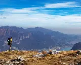 Escursionista ammira la vista panoramica di una montagna vicino Milano, con un lago e un paese in lontananza.