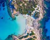 Spiaggia paradisiaca con acque cristalline, perfetta per itinerari Sardegna nord 7 giorni. Ombrelloni e lettini invitano al relax.
