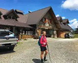 Ragazza con zaino e bastoncini da trekking davanti a un rifugio alpino, una delle tipiche malghe in Friuli.
