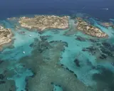 Acque cristalline e isolotti rocciosi, un paradiso dove si trova la Maddalena. Barche navigano in questo mare turchese.