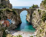 Un ponte ad arco domina un fiordo con case colorate aggrappate alla roccia. Il **furore costiera amalfitana** è un incanto tra mare turchese e sentieri scoscesi.