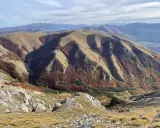 Autunno nel Val di Norcia, con montagne dolci e boschi dai colori caldi che scendono verso la valle.