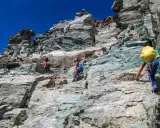 Alpinisti scalano la roccia sul Monviso, seguendo la via normale. Un'avventura sotto il cielo azzurro.