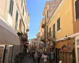 Passeggiata in un vicolo colorato, ideale per visitare La Maddalena in auto, con edifici storici e negozietti.