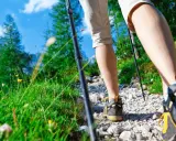 Camminando sul sentiero dei poeti, tra erba verde e fiori gialli, con bastoncini da trekking e scarponi da montagna.