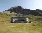 Un imponente rifugio in pietra, incastonato tra prati verdi e rocce imponenti, domina il paesaggio alpino. Un luogo ideale per chi cerca avventura e tranquillità nel cuore della Valle d'Aosta.