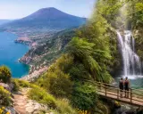 Sentiero costiera amalfitana: vista panoramica sul golfo con il Vesuvio e una cascata nascosta tra la vegetazione.