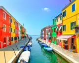 Colorate case affacciate su un canale con barche ormeggiate, un'incantevole scena di **Murano e Burano**.