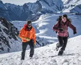 Coppia in montagna con abbigliamento da neve, godendosi l'estate in un paesaggio innevato.