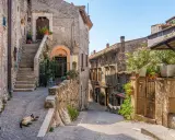Un gatto si gode il sole in un vicolo acciottolato, tra antiche case di pietra e scale ripide. Un'atmosfera autentica di borghi da visitare nel nord Italia.