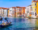 Gondole e vaporetti sul Canal Grande, un assaggio di cosa vedere a Venezia in due giorni. Palazzi colorati e acqua scintillante.