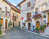 Antica via acciottolata tra **borghi Abruzzo sul mare**, con case in pietra e fiori colorati sui balconi.