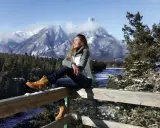 Ragazza con gita outfit montagna estate, gode del panorama innevato.