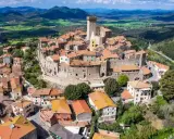 Un borgo medievale con un castello domina le colline toscane. Perfetto per un weekend in Toscana, tra tetti rossi e panorami mozzafiato.