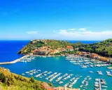 Porto Ercole, con le sue splendide spiagge e il porto pieno di barche, incanta sotto un cielo azzurro.