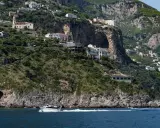 Un traghetto da Amalfi a Positano sfreccia nel mare blu, con case bianche aggrappate alle scogliere verdi.
