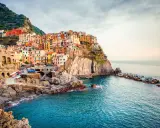 Manarola, uno dei borghi italiani da visitare, si aggrappa alla scogliera con le sue case colorate che si tuffano nel mare blu.