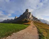 Sentiero per escursioni al Passo Giau, con imponenti vette rocciose e un rifugio alpino.