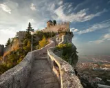 Sentiero in pietra che sale verso la Rocca della Guaita, simbolo di San Marino città, con vista panoramica sulla valle.