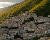 Borgo San Donato, un incantevole paese arroccato su un colle, immerso nel verde di una montagna illuminata dal sole al tramonto.