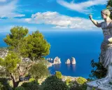 Statua antica guarda il mare blu intenso e i Faraglioni, icona dell'isola vicino Capri.