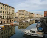 Canali e palazzi storici a Livorno, perfetti per gite di un giorno. Barche ormeggiate riflettono l'architettura.