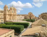 Piazza barocca con chiese imponenti e giardini curati, un esempio delle citta piu belle d'Italia.