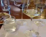 Calici di vino bianco e rosso, pane tostato e acqua per una degustazione vini Bolgheri.
