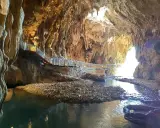 Sentiero illuminato lungo un ruscello nelle grotte di Pastena, tra stalattiti e stalagmiti dorate.