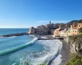 Colorati borghi medievali vicino a Genova, con onde turchesi che si infrangono sulla spiaggia di ciottoli.