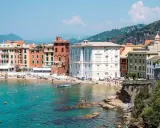 Colorate case affacciate su una spiaggia affollata e un mare turchese, tipico della riviera di Levante.