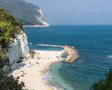 Spiaggia dorata con scogliere bianche e mare cristallino, un angolo di paradiso tra le migliori spiagge del nord Italia.