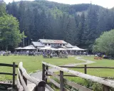 Un rifugio in Emilia Romagna immerso nel verde, con tavoli all'aperto e persone che si godono la giornata.