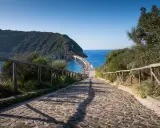 Sentiero acciottolato verso un ponte sul mare, ideale per cammini in Italia sul mare.